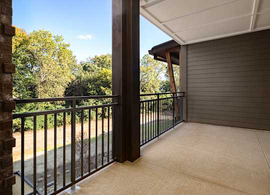 A balcony with a black railing and a view of trees.