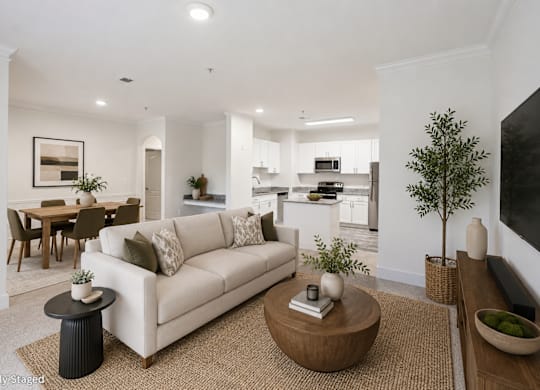 A living room with a white couch, a coffee table, and a dining table.