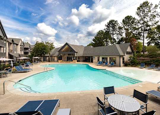 A large outdoor swimming pool surrounded by lounge chairs and umbrellas.