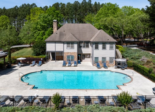 a large pool in front of a house with chairs around it