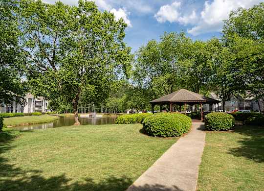 A gazebo is surrounded by greenery in a park.