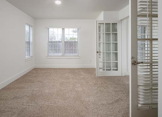 A room with french doors, a carpeted floor and a door with a window.