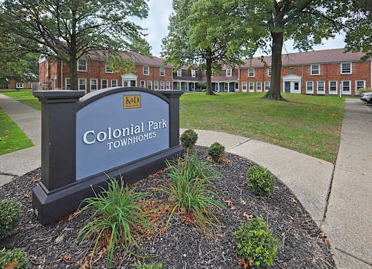 A sign that says Colonial Park Townhomes in front of some buildings.
