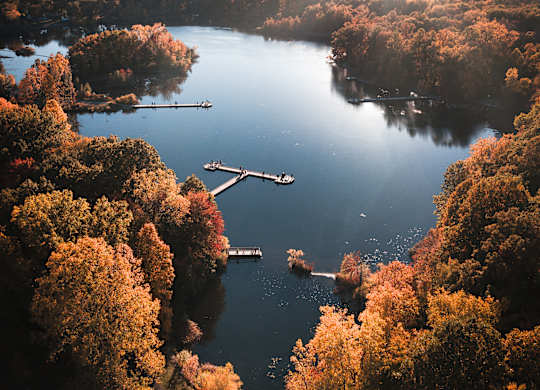 A serene lake surrounded by autumn trees with boats sailing on the water.