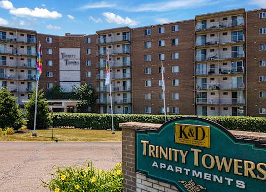 A sign for Trinity Towers Apartments is in front of a brick building.