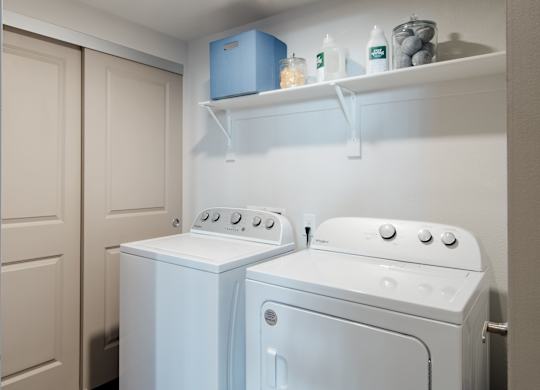 a white washer and dryer in a small laundry room with a shelf above at Parkside at Littleton Village, Littleton, CO