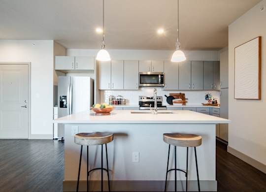 a kitchen with two stools in front of a counter top at Parkside at Littleton Village, Littleton