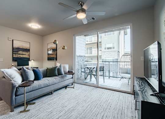 a living room with a couch and a sliding glass door to a balcony at Parkside at Littleton Village, Littleton