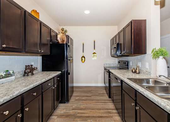 A kitchen with dark brown cabinets and a black refrigerator.