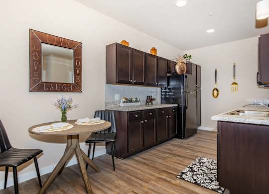A kitchen with a table and chairs and a fridge.