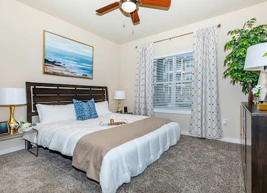 A bedroom with a large bed and a ceiling fan.