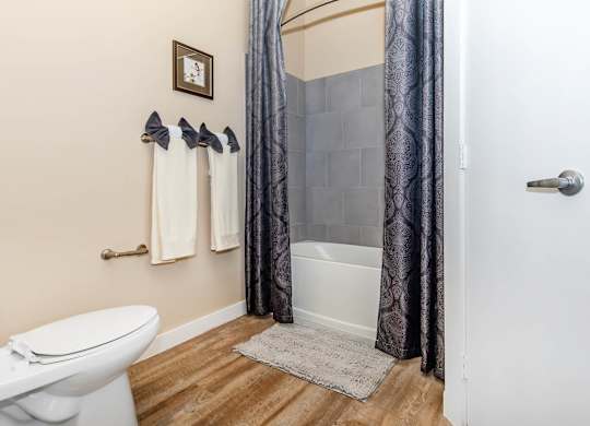 A white toilet sits next to a white bathtub in a bathroom.