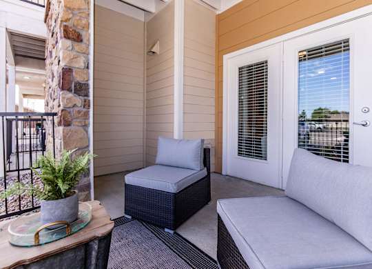 A patio with a couch, chair, and table.