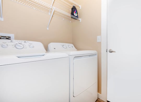 Two white front loading washing machines in a small laundry room.