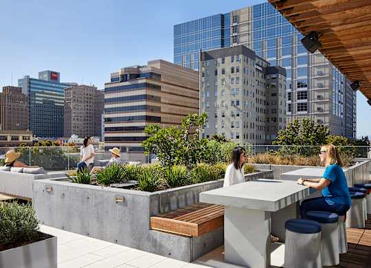Two women are sitting at a table on a rooftop patio.