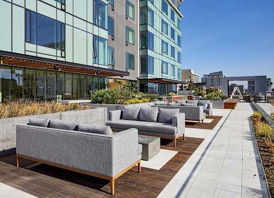 A patio with grey couches and wooden tables.