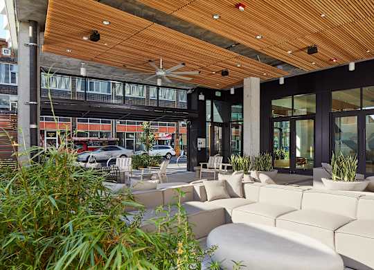 A patio with white couches and a wooden ceiling.