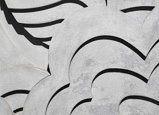 A close up of a white and black patterned artwork on the wall.