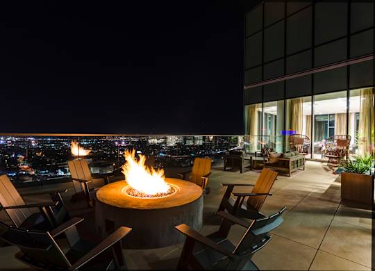 A fire pit sits in the middle of a patio with chairs around it.