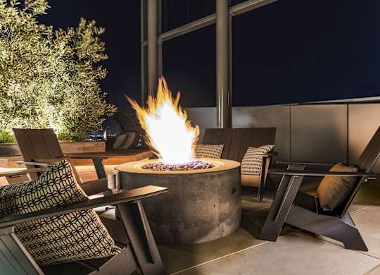 A fire pit in the middle of a patio surrounded by chairs.