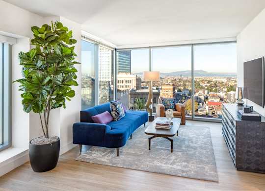A living room with a blue couch and a large window overlooking the city.