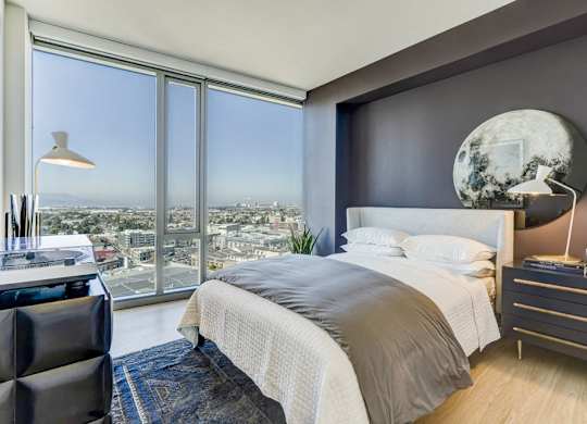 A modern bedroom with a large bed and a view of the city.