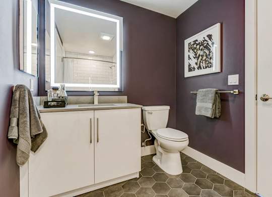 A bathroom with a toilet, sink, and mirror.