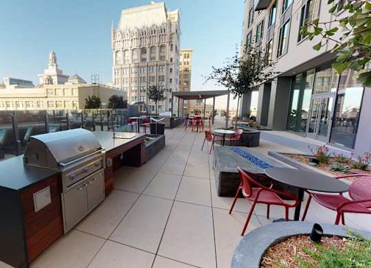 A rooftop patio with tables and chairs and a grill.