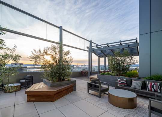 A rooftop patio with a table, chairs, and a bench.