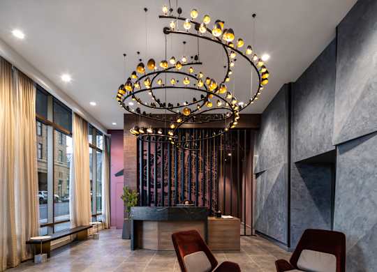 A modern living room with a large chandelier and two chairs.