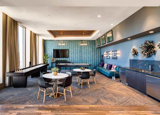 A modern living room with a pool table and a kitchen area.