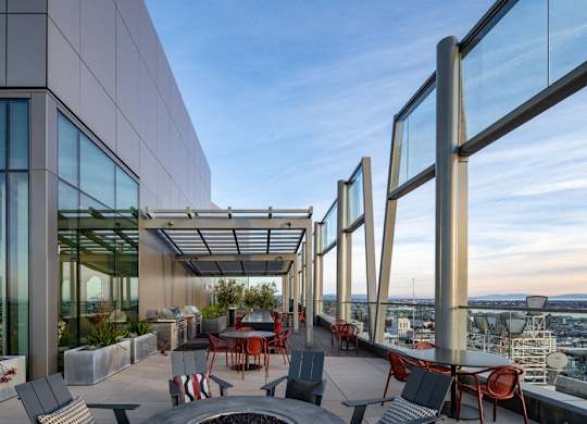 A rooftop patio with a table and chairs overlooking a cityscape.