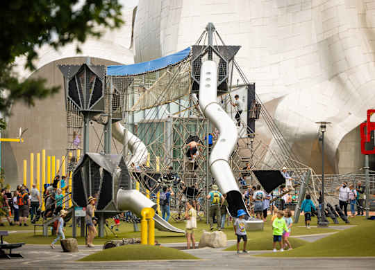 Large playground structure with modern architecture backdrop at Axis Seattle Apartments, Washington, 98109