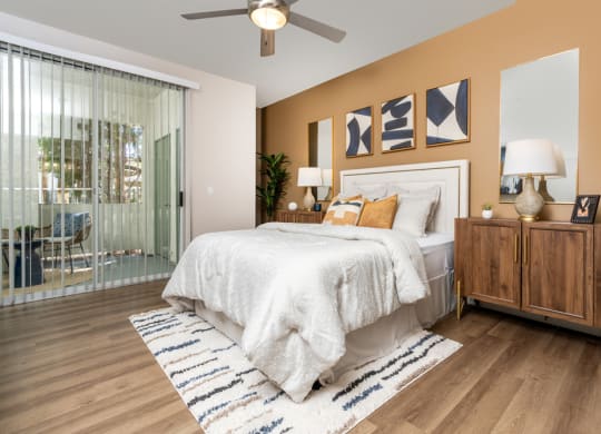 Apartments Spring Valley, NV - Alicante - Bedroom Featuring Hardwood-Style Floors, Ceiling Fan, Large Sliding Glass Door to Patio