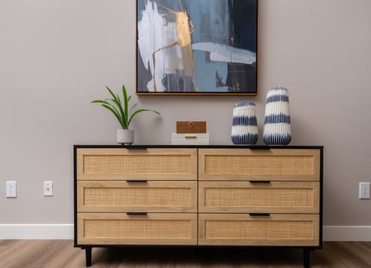 a dresser with four drawers and a painting on the wall