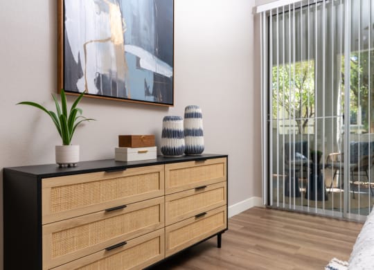 a living room with a dresser and a window with a sliding glass door