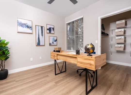 a home office with a wooden desk and a large window