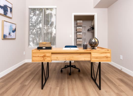 a home office with a wooden desk and a large window