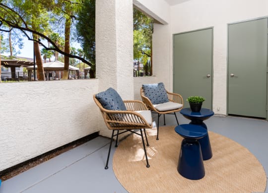 a patio with two chairs and a table and a door