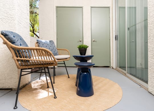 a patio with two chairs and a table and a door
