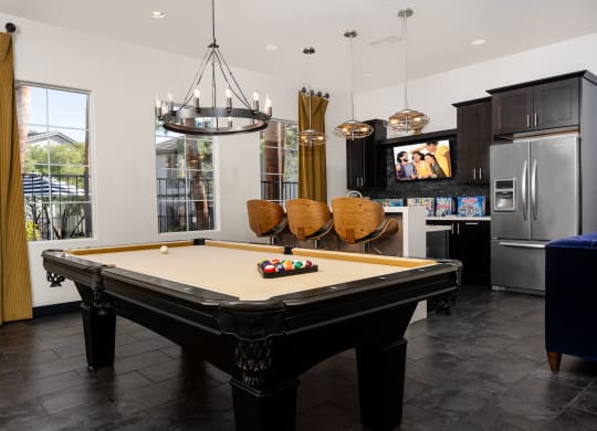 a billiards table in a living room with a kitchen and television