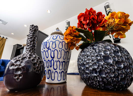 three vases on a wooden table with flowers