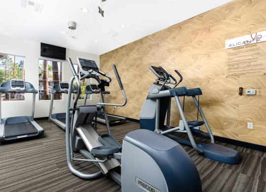 a gym with cardio equipment and weights on a wall