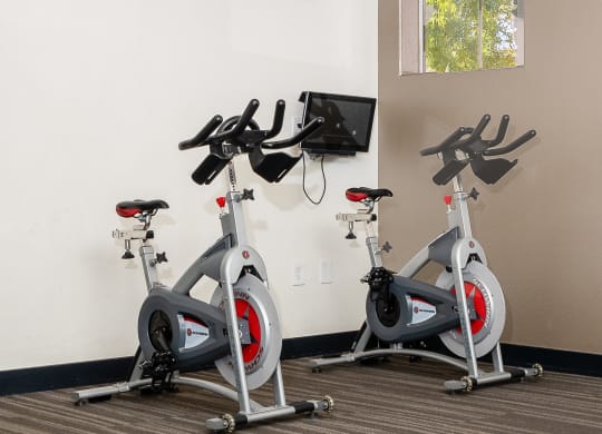 an indoor gym with three exercise bikes and a picture of a man with his arms