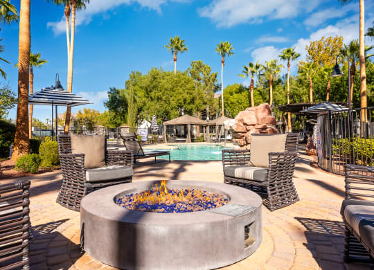 an outdoor patio with a fire pit and chairs and a pool