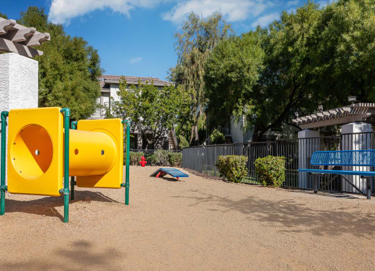 a playground with yellow and blue playground equipment and a blue bench