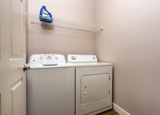 the laundry room has a washer and dryer and a shelf above the door