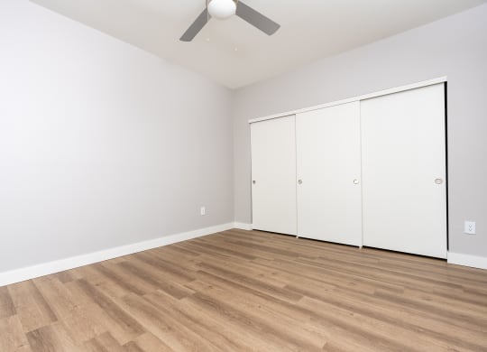 a living room with white walls and wood flooring and a ceiling fan