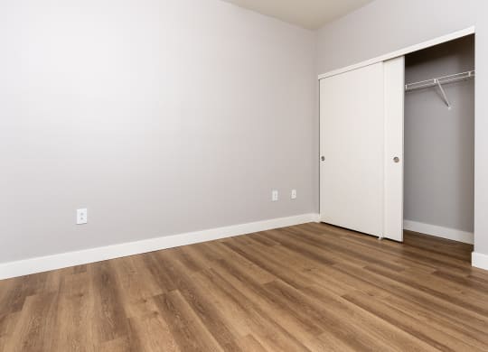 an empty room with a closet and wood flooring