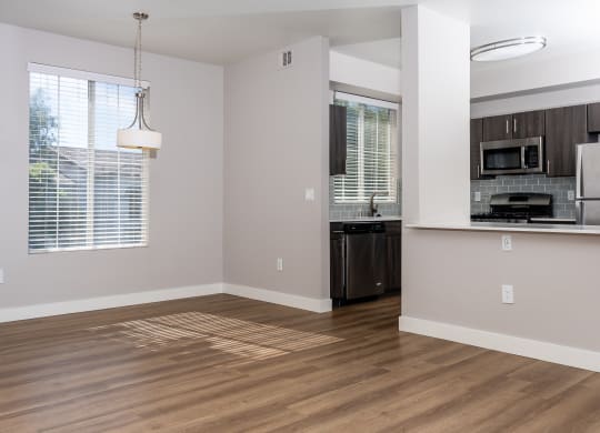 an empty kitchen and living room with wood flooring and a window